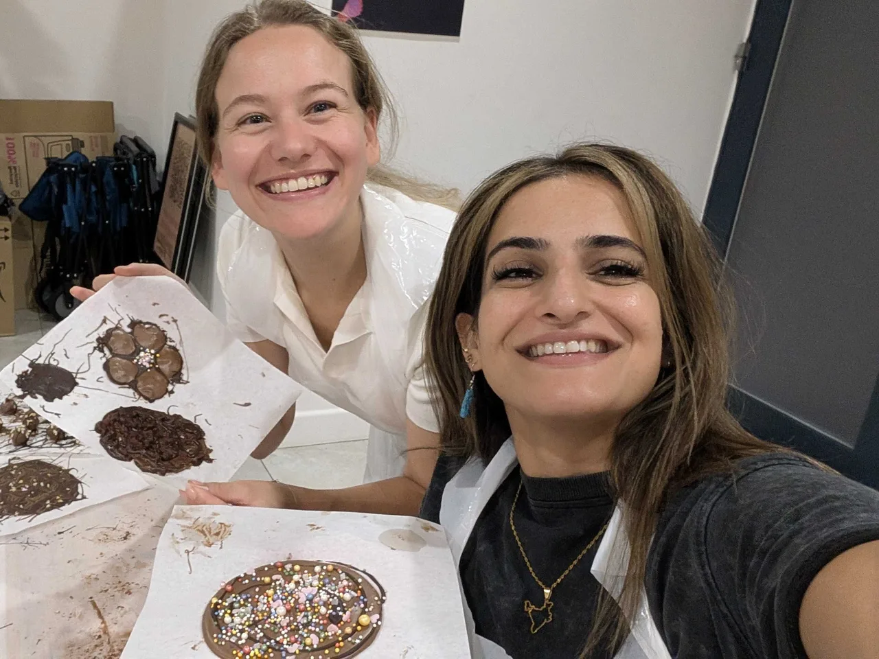 Two colleagues holding up chocolate discs they decorated at a chocolate making workshop